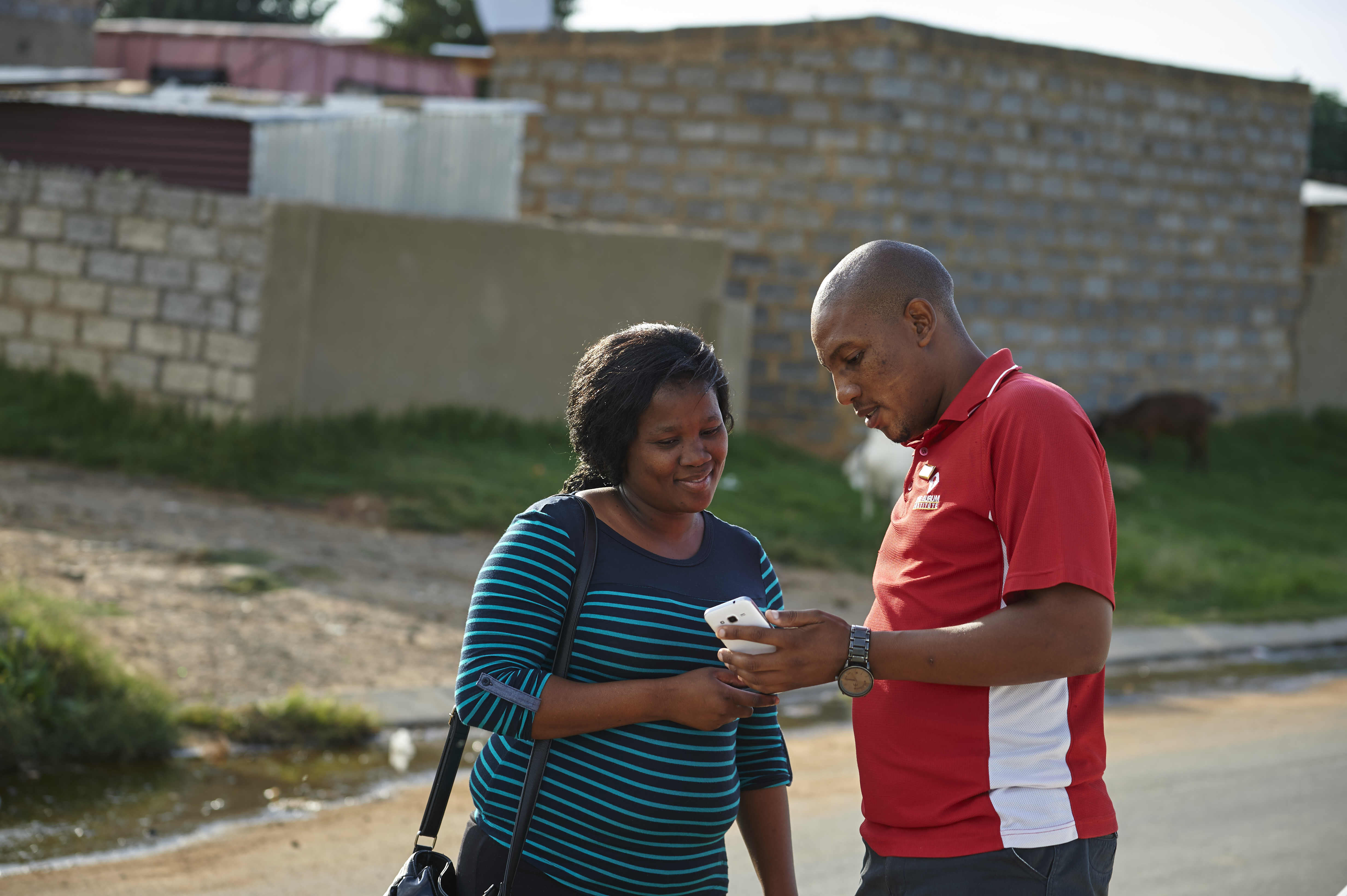 An Aurum staff member showing a community member information on a phone